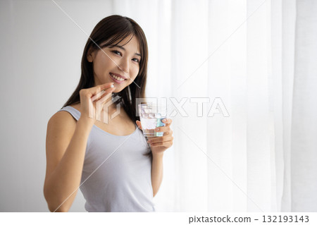一位年輕女子在窗邊服用補充劑 132193143