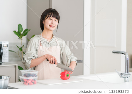 Young Asian woman in an apron cooking in the kitchen 132193273