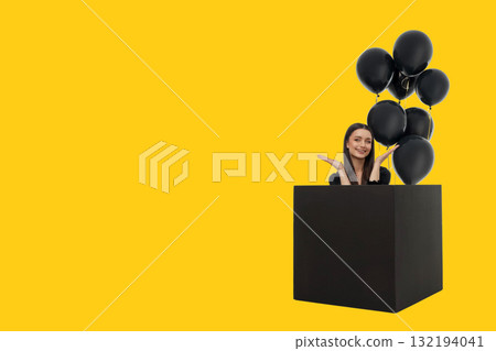 Cheerful woman with long hair in a black box with balloons Cheerful woman with long hair in a black box with balloons 132194041