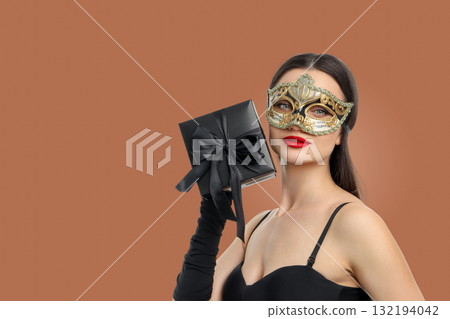 Woman in elegant attire holds a gift wrapped with a bow Woman in elegant attire holds a gift wrapped with a bow 132194042