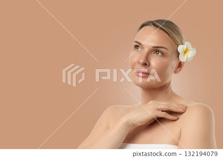 Woman calms herself, touching her shoulder, flower in hair 132194079