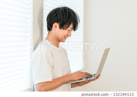 Young Asian man looking at laptop in the living room at home 132194113
