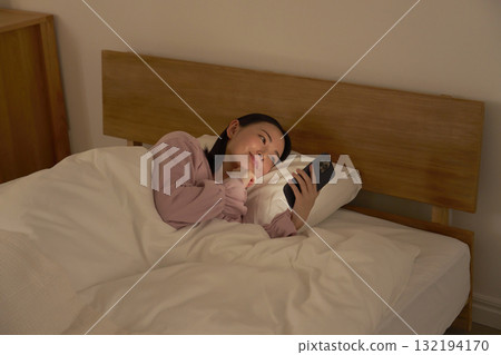 A woman using a smartphone in bed 132194170