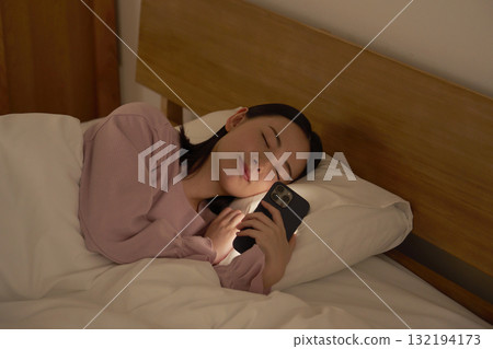 A woman falls asleep while using her smartphone in bed 132194173