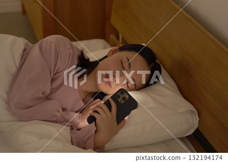 A woman falls asleep while using her smartphone in bed 132194174