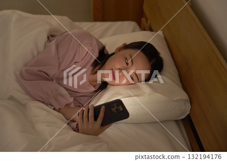 Woman looking at smartphone in futon Woman looking at smartphone in futon 132194176