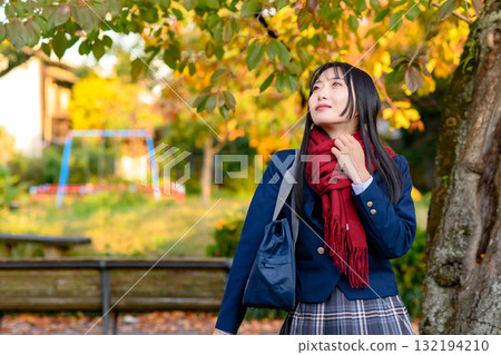 一名高中女生在秋葉的襯托下休息,一名高中生穿著冬裝,去上學,修剪整齊 一名高中女生在秋葉的襯托下休息,一名高中生穿著冬裝,去上學,修剪整齊 132194210