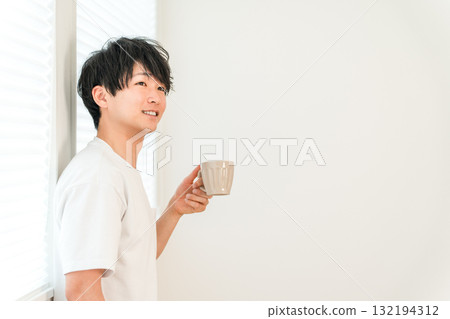 亞洲年輕男子在窗邊喝熱飲、茶、咖啡 亞洲年輕男子在窗邊喝熱飲、茶、咖啡 132194312