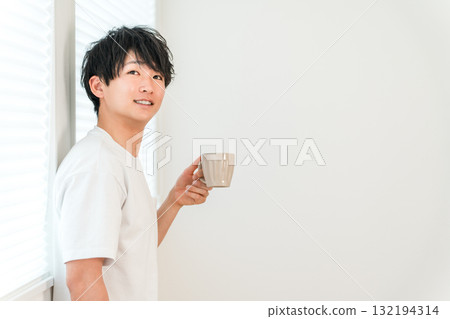 亞洲年輕男子在窗邊喝熱飲、茶、咖啡 亞洲年輕男子在窗邊喝熱飲、茶、咖啡 132194314