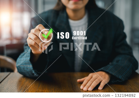Businesswoman pointing to ISO 9001 certification symbolizing quality management and standards in a professional office environment. 132194892