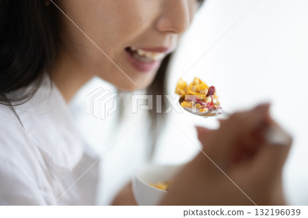 Close-up of a woman spooning cereal into her mouth Close-up of a woman spooning cereal into her mouth 132196039