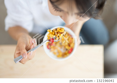 Close-up of a woman spooning cereal into her mouth 132196041