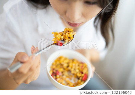 Close-up of a woman spooning cereal into her mouth Close-up of a woman spooning cereal into her mouth 132196043