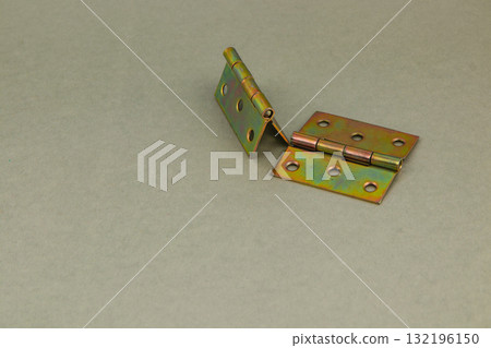 Metal hinge resting on a flat surface with a green and brown finish 132196150