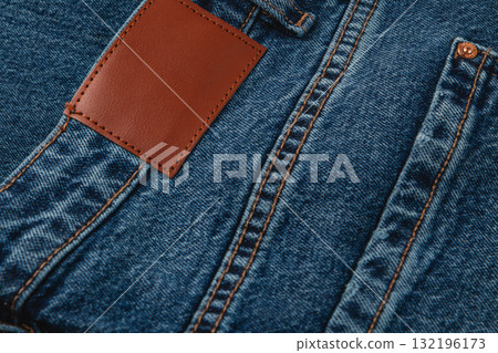 Close-up of denim fabric with leather label showing intricate stitching 132196173