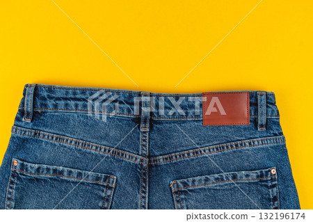 Denim jeans with brown leather patch on bright yellow background 132196174