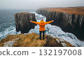 Person with arms outstretched enjoying dramatic coastal view cliffs ocean waves 132197008