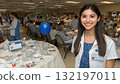 Smiling young woman in medical uniform at a large indoor event 132197011