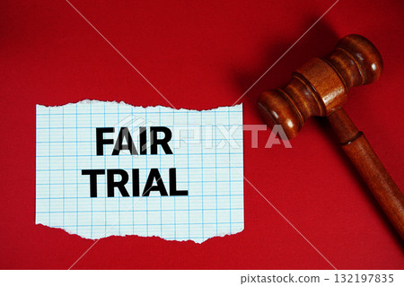 Fair Trial text written on rip paper with wooden judgment gavel on red background Fair Trial text written on rip paper with wooden judgment gavel on red background 132197835