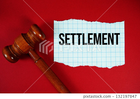 Settlement text written on rip paper with wooden judgment gavel on red background 132197847