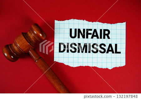 Unfair Dismissal text written on rip paper with wooden judgment gavel on red background Unfair Dismissal text written on rip paper with wooden judgment gavel on red background 132197848