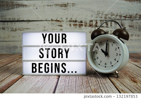 Your Story Begins... text with alarm clock on wooden background Your Story Begins... text with alarm clock on wooden background 132197853