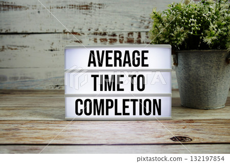 Average Time to Completion text with alarm clock on wooden background 132197854