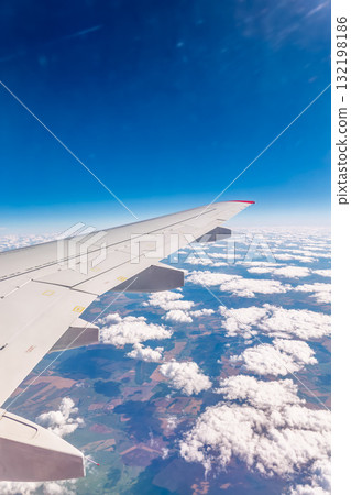 View from the airplane window at a beautiful cloudy sky and the airplane wing View from the airplane window at a beautiful cloudy sky and the airplane wing 132198186