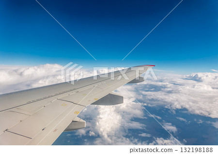 View from the airplane window at a beautiful cloudy sky and the airplane wing View from the airplane window at a beautiful cloudy sky and the airplane wing 132198188