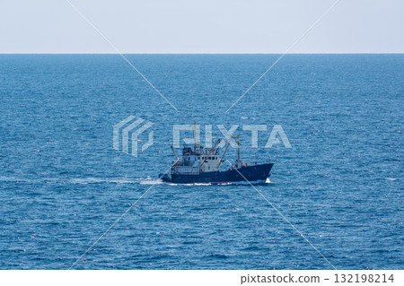 Fishing boat in blue sea and clear sky with birds flying overhead. 132198214