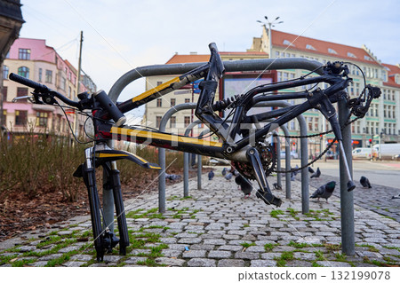 Damaged bicycle frame locked to bike rack on city street Damaged bicycle frame locked to bike rack on city street 132199078