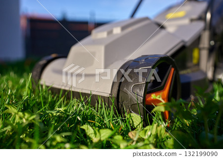 Electric lawnmower on green grass in backyard 132199090