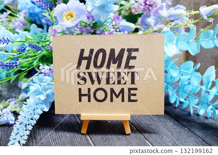 Home Sweet Home text write on paper card with wooden easel and flowers decoration on wooden background 132199162