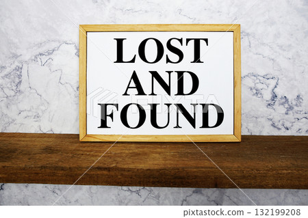 Blackboard with text "Lost And Found" on a wooden shelf, set against a marble wall. 132199208