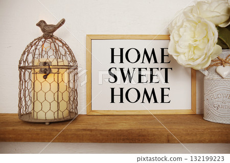 Home Sweet Home text written on whiteboard with LED candle light and bird cage on wooden shelf Home Sweet Home text written on whiteboard with LED candle light and bird cage on wooden shelf 132199223