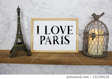 I Love Paris text written on whiteboard with Eiffel Tower Souvenir and bird cage with candle light I Love Paris text written on whiteboard with Eiffel Tower Souvenir and bird cage with candle light 132199226