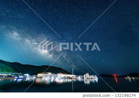 在座頭鯨雕像旁的海灘上拍攝的長曝光星空照片。銀河和流星清晰可見。港口裡可以看到漁船和其他東西。座間味島 132199274