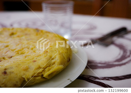 Homemade Spanish omelette on a white plate with a glass in the background Homemade Spanish omelette on a white plate with a glass in the background 132199600