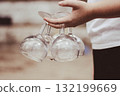 Hand holding several wine glasses outdoors 132199669