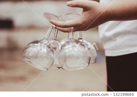 Hand holding several wine glasses outdoors 132199669