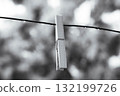 Minimalist black and white photo of a clothespin with raindrops on a wire 132199726