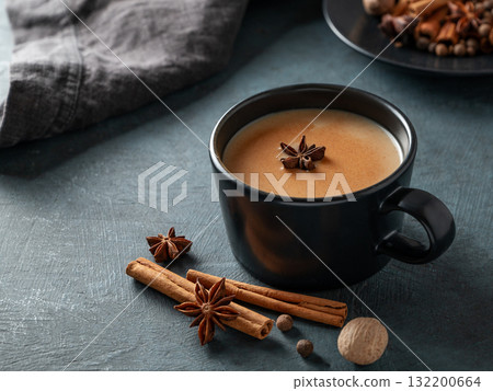 Traditional Indian masala chai tea with milk and spices in a black cup on a dark background Traditional Indian masala chai tea with milk and spices in a black cup on a dark background 132200664