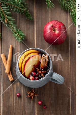 A cup of red mulled wine with spices, orange, apple slices and cranberry on a wooden background A cup of red mulled wine with spices, orange, apple slices and cranberry on a wooden background 132200666