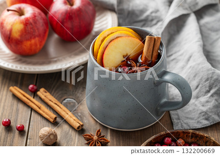 A cup of red mulled wine with spices, orange, apple slices and cranberry on a wooden background A cup of red mulled wine with spices, orange, apple slices and cranberry on a wooden background 132200669