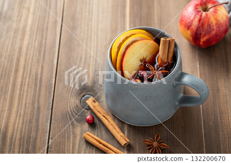 A cup of red mulled wine with spices, orange, apple slices and cranberry on a wooden background A cup of red mulled wine with spices, orange, apple slices and cranberry on a wooden background 132200670