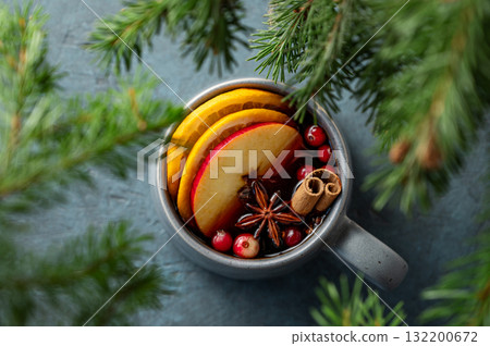 A cup of red mulled wine with spices, orange, apple slices and cranberry on a dark background  132200672