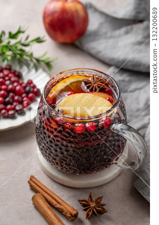 A cup of red mulled wine with spices, orange, apple slices and cranberry on a light background A cup of red mulled wine with spices, orange, apple slices and cranberry on a light background 132200689