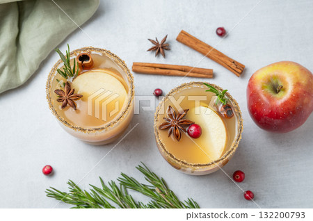 Two glasses of apple cider with cinnamon, anise, brown sugar and rosemary on a light background 132200793