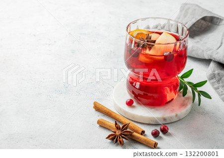 A cranberry drink in a glass on a light background with cinnamon and napkin. A cranberry drink in a glass on a light background with cinnamon and napkin. 132200801