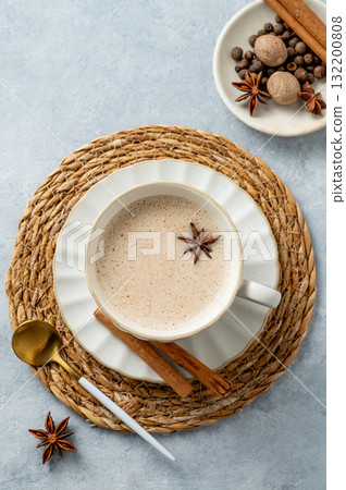 Traditional Indian masala chai tea with milk and spices in a white cup on a light blue background Traditional Indian masala chai tea with milk and spices in a white cup on a light blue background 132200808